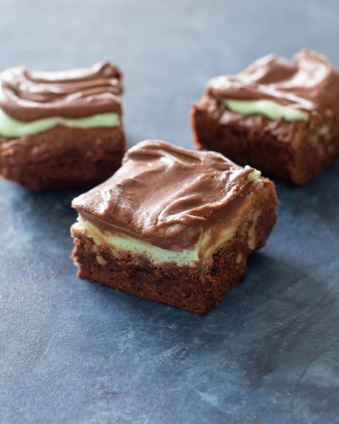 brownies with frosting on a blue board