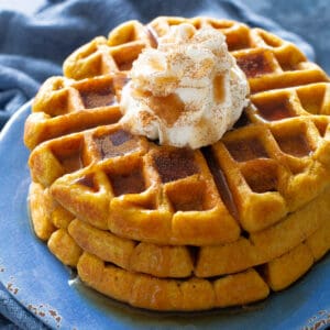 pumpkin waffles with whipped cream on a blue plate