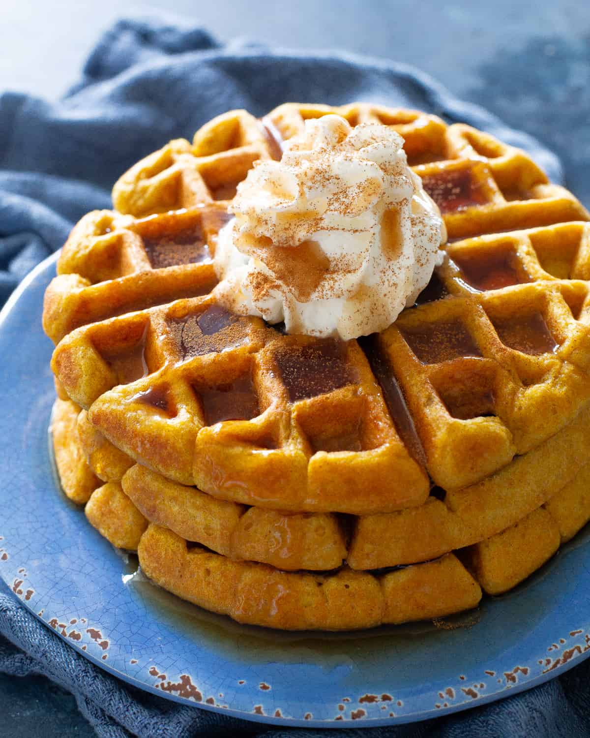 pumpkin waffles with whipped cream on a blue plate