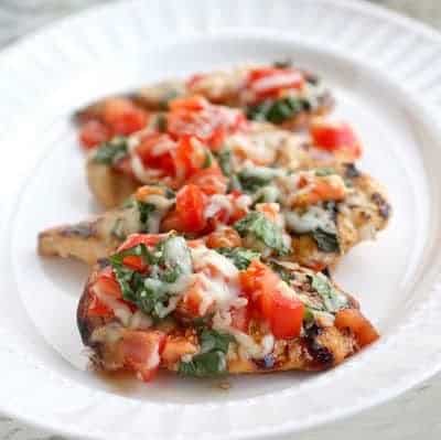 This Grilled Chicken Bruschetta is one of our healthy go-to meals topped with marinated tomatoes, basil, and cheese. the-girl-who-ate-everything.com