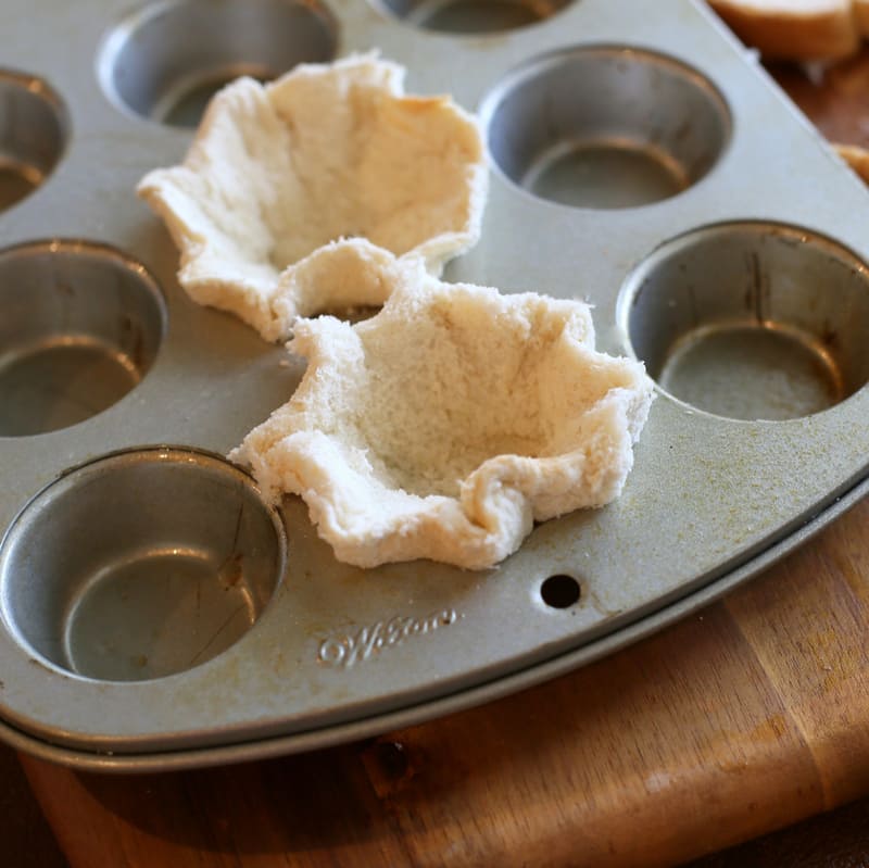 bread being pressed in a muffin tin