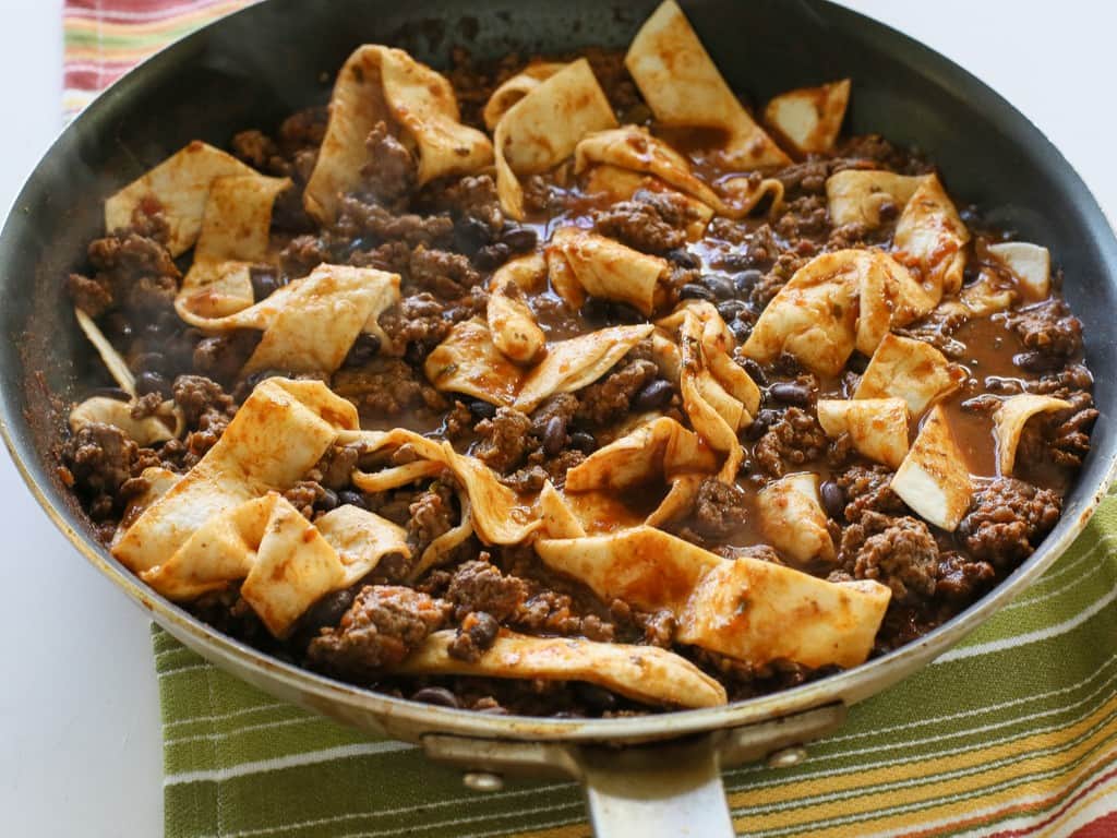 This Easy Beef Burrito Skillet has beef, black beans, salsa, and tortillas all cooked in one skillet. The tortillas turn soft and almost like a dumpling. This tasty dish is done in less than 20 minutes. the-girl-who-ate-everything.com