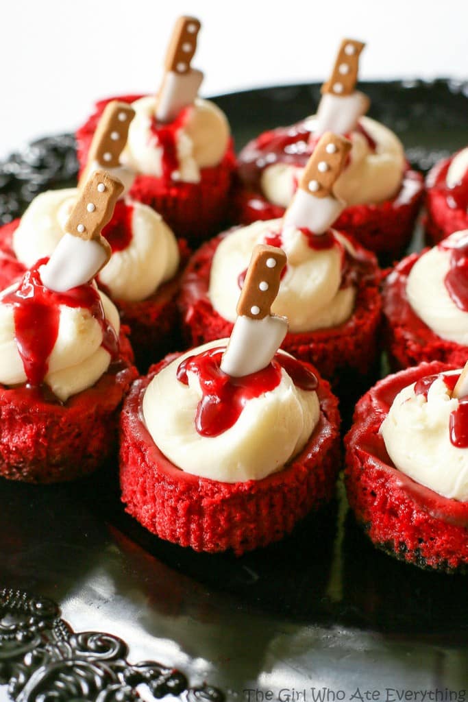 Mini Red Velvet Cheesecakes - moist red velvet cheesecake with an Oreo crust. The best recipe I've ever had. Topped with cream cheese for the ultimate indulgence. Add some edible blood for a dramatic Halloween dessert. the-girl-who-ate-everything.com