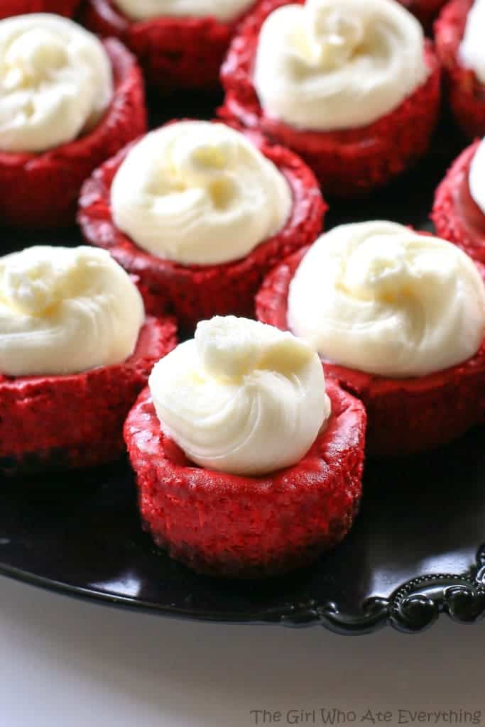 Mini Red Velvet Cheesecakes - moist red velvet cheesecake with an Oreo crust. Topped with cream cheese for the ultimate indulgence. Great for Christmas or Valentine's Day. the-girl-who-ate-everything.com
