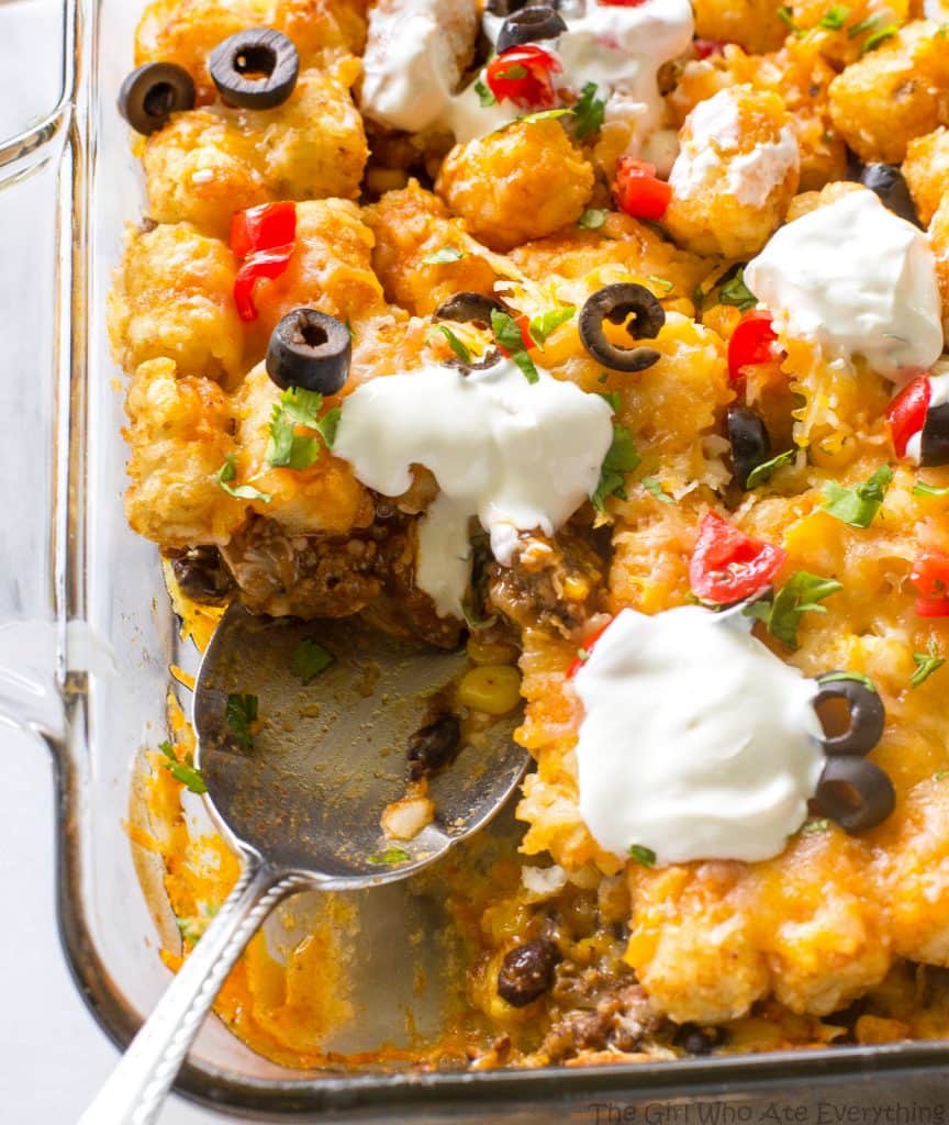 Tater Taco Casserole - A Mexican mixture of taco meat, beans, corn, and cheese topped with tater tots and enchilada sauce. the-girl-who-ate-everything.com