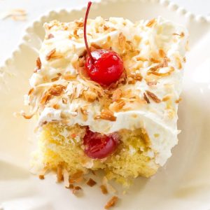 Pina Colada Poke Cake - drizzled with coconut and pineapple and topped with coconut whipped cream and toasted coconut, this cake is the best summer cake out there. the-girl-who-ate-everything.com