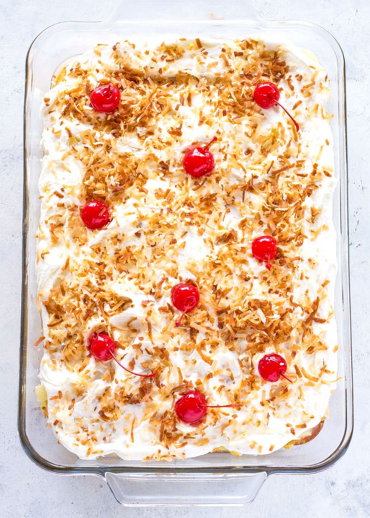 Pina Colada Poke Cake - drizzled with coconut and pineapple and topped with coconut whipped cream and toasted coconut, this cake is the best summer cake out there. the-girl-who-ate-everything.com