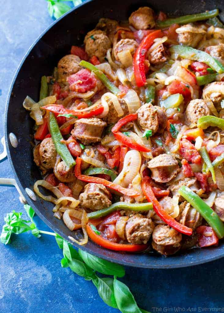 sliced sausage, green and red bell peppers and onions in a pan