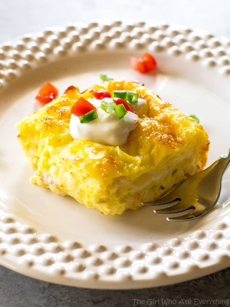 Cheesy Baked Eggs slice with sour cream, tomato, and green onions