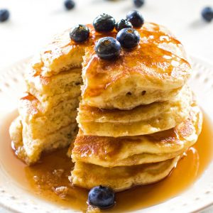 Fluffy pancakes and blueberries with syrup on a plate