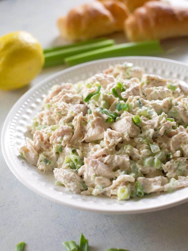 chicken salad on a white plate with a lemon