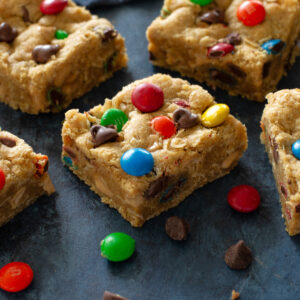 monster cookie dough bars on a blue surface with M&Ms